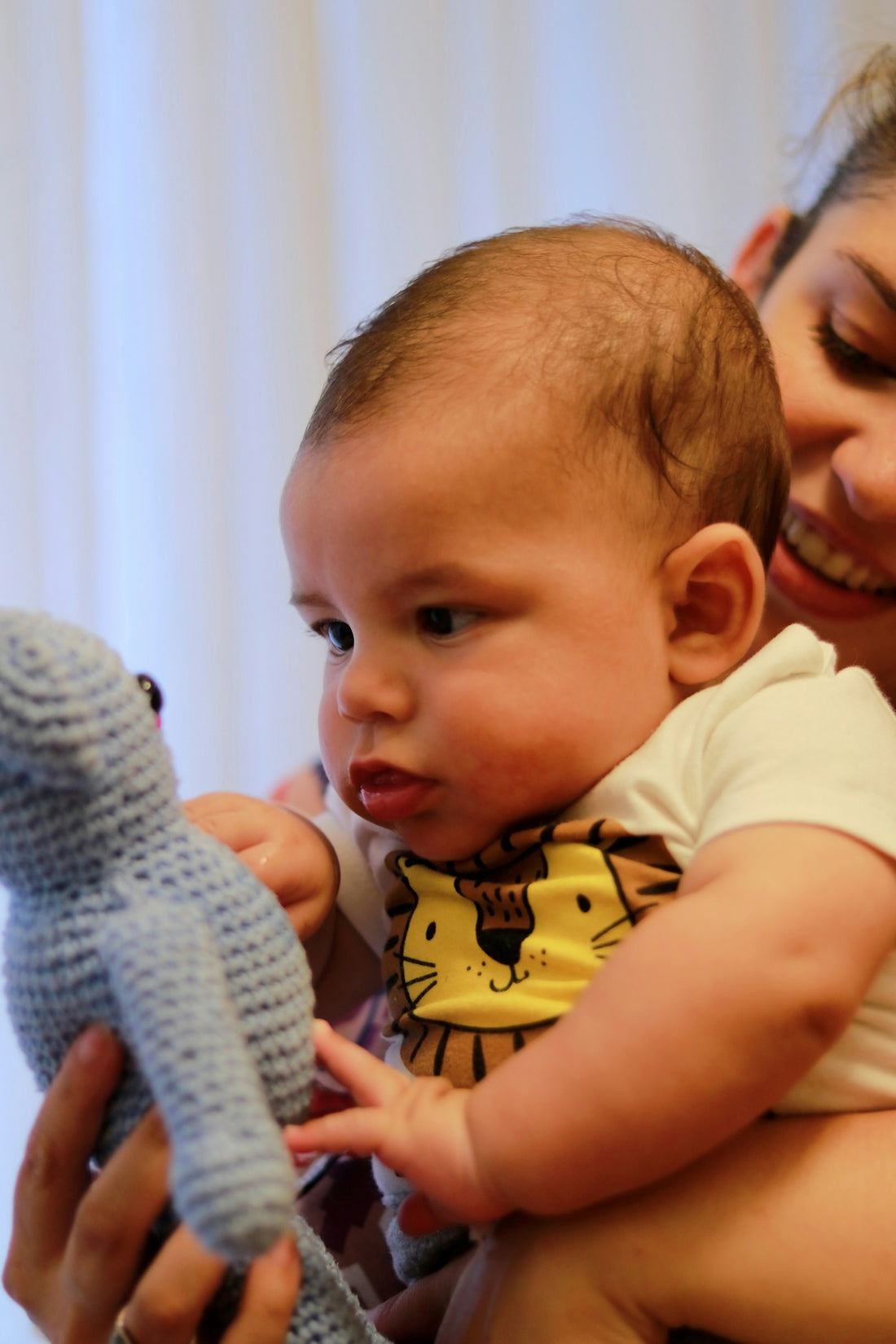 a woman holding a baby who is holding a stuffed animal