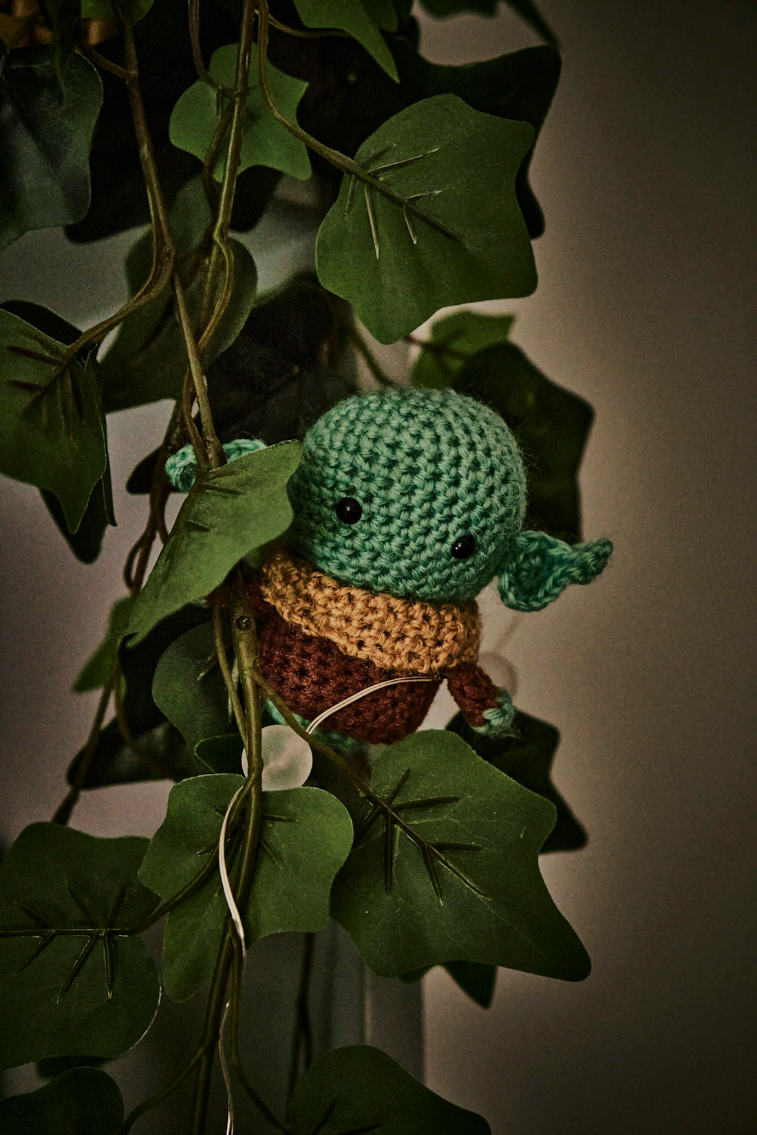 a crocheted yoda is hanging from a plant