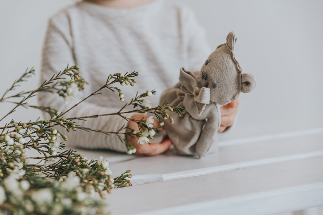 a person holding a stuffed animal next to a plant
