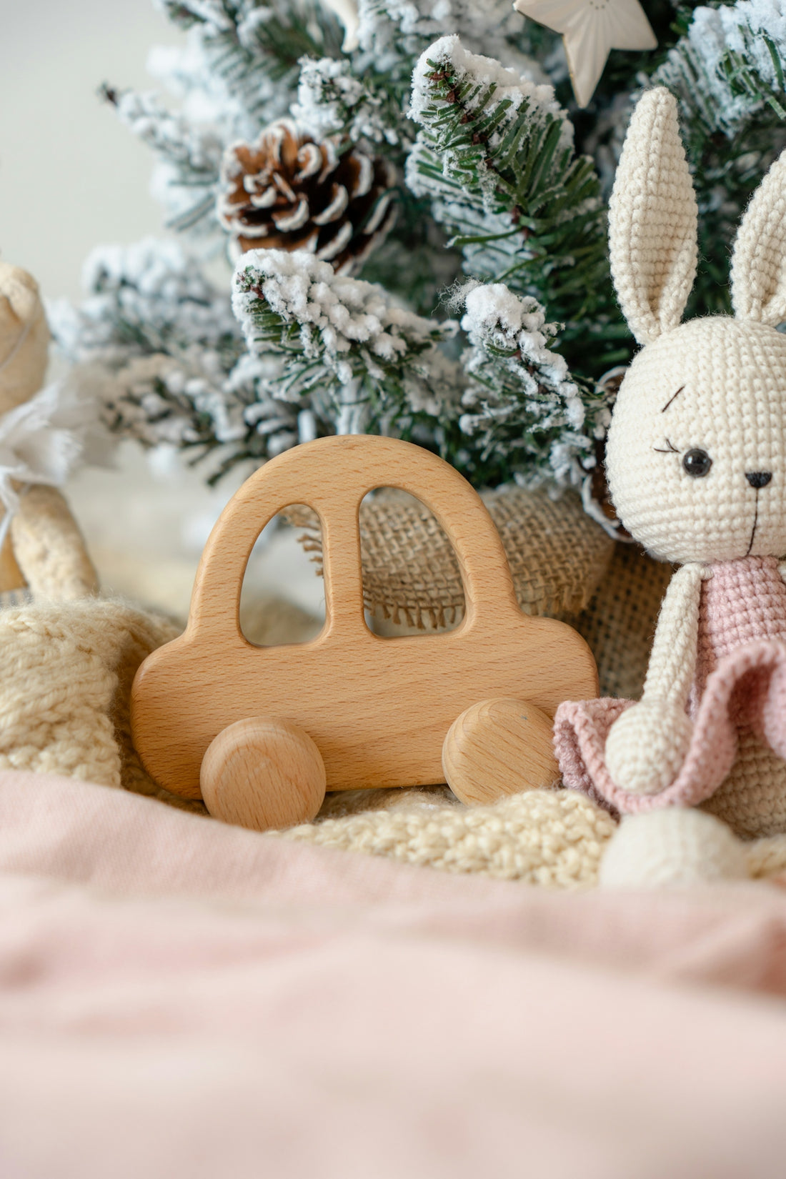 A crocheted bunny sitting next to a toy car
