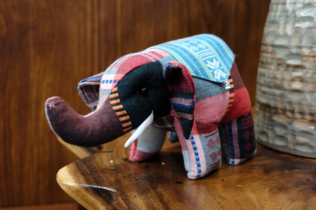 A stuffed elephant sitting on top of a wooden chair
