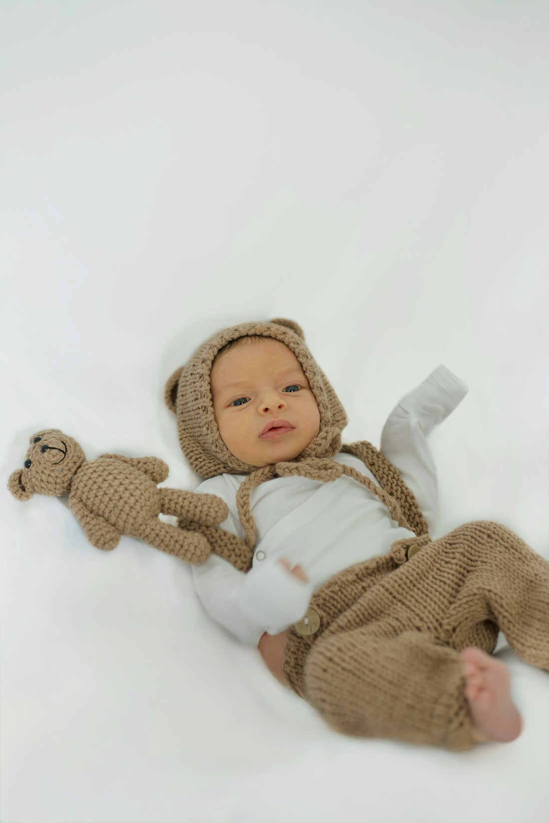 Cute baby dressed as a bear and holding a toy.