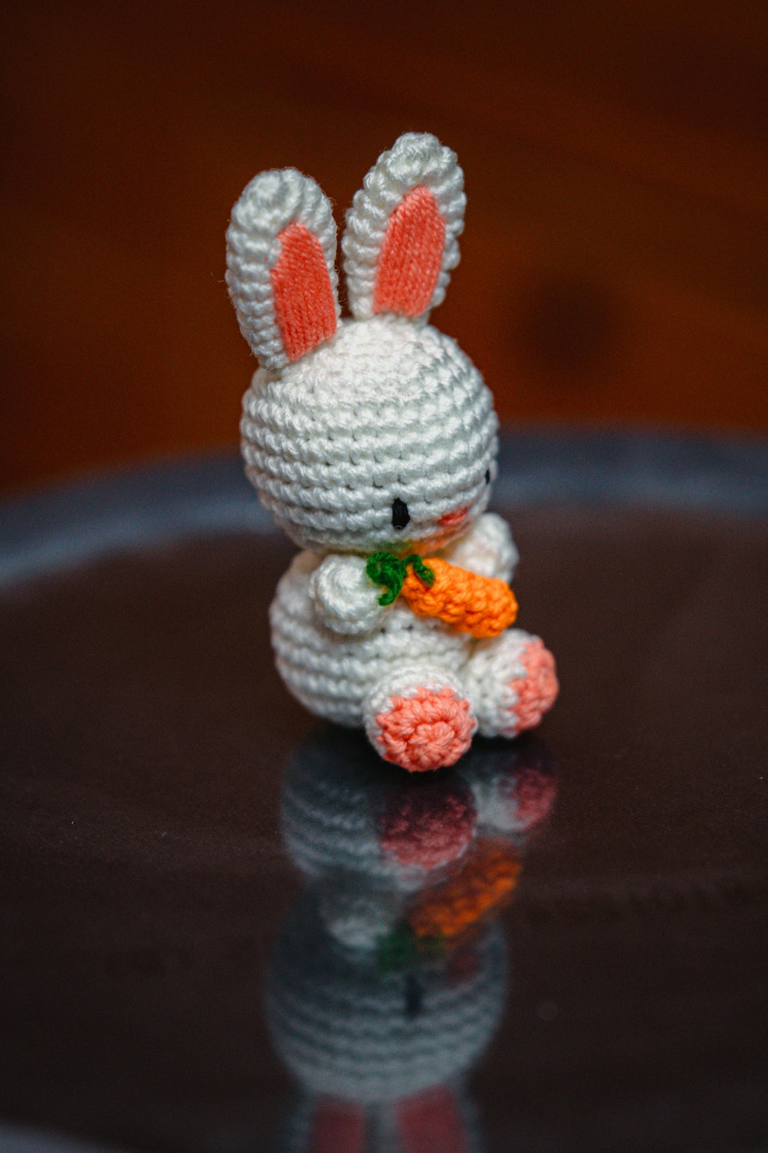 A cute crochet bunny holds a carrot.